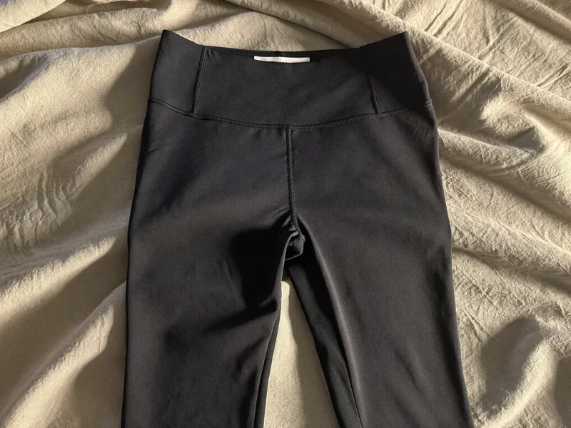Leggings a vita alta distesi su una superficie in lino con luce laterale